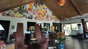 A spacious lobby with a high ceiling, a large fan, and a vibrant mural. - Segara Villas (Olongapo)