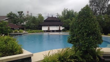 Una piscina al aire libre, sombrillas, sillones reclinables de piscina