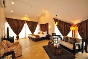 A hotel room with a bed, a sofa, a coffee table, and curtains. - Segara Villas (Olongapo)
