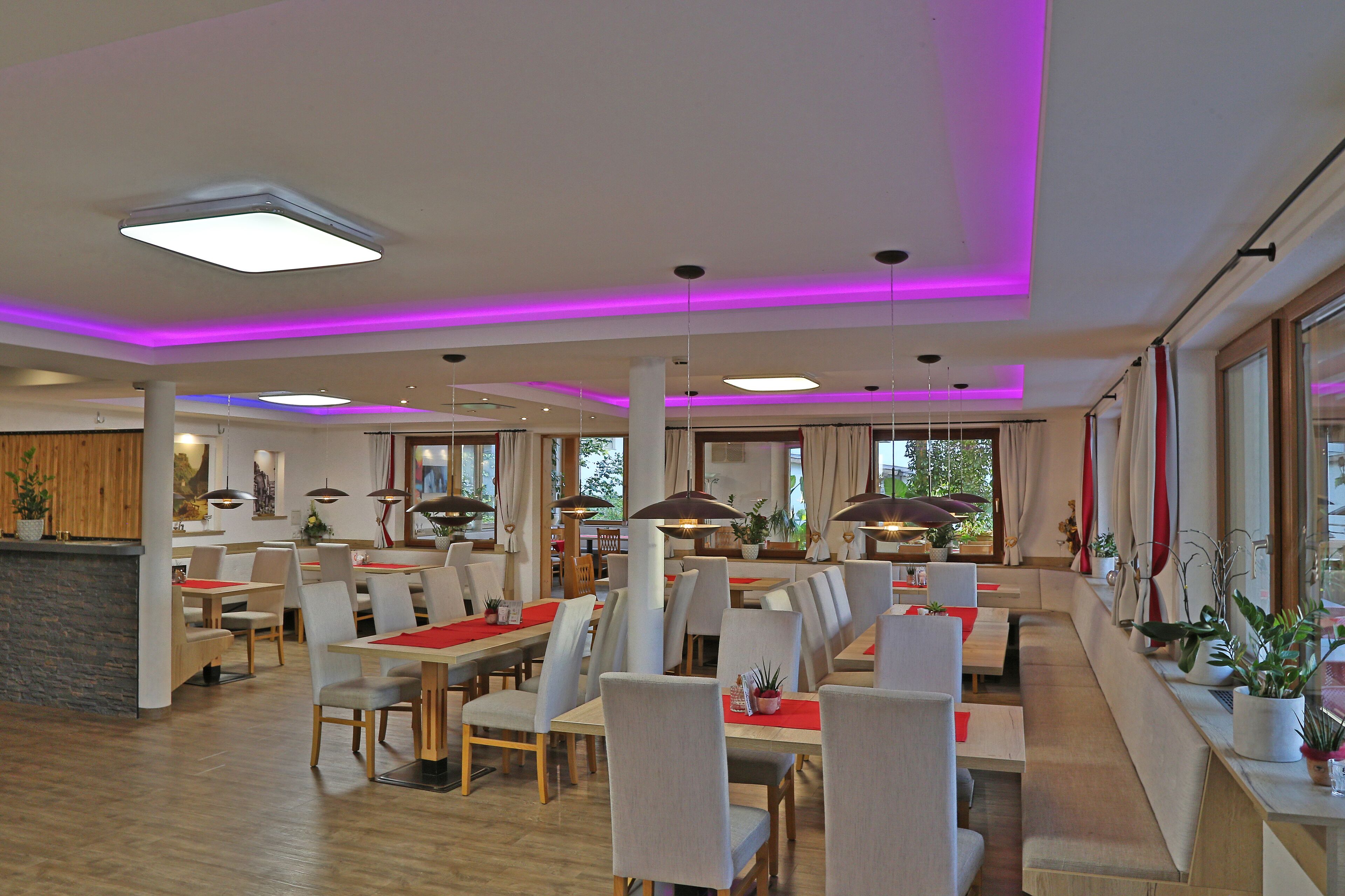 Un restaurant spacieux avec de hauts plafonds, des luminaires suspendus et un décor intérieur moderne.