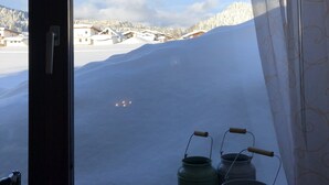 A window view of a snowy landscape with buildings in the distance. - Gasthof Pension Posthansl (Heiterwang)