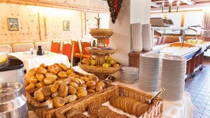 A buffet with various breads, fruits, and stacked plates. - Hotel Thaler (Thiersee)