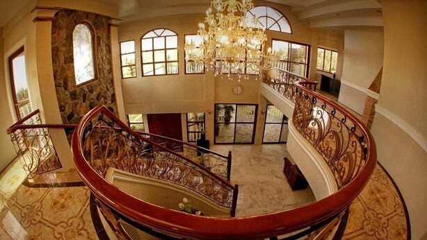 Un intérieur spacieux à plusieurs niveaux, doté d’un escalier en colimaçon central, de grandes fenêtres et d’un lustre.