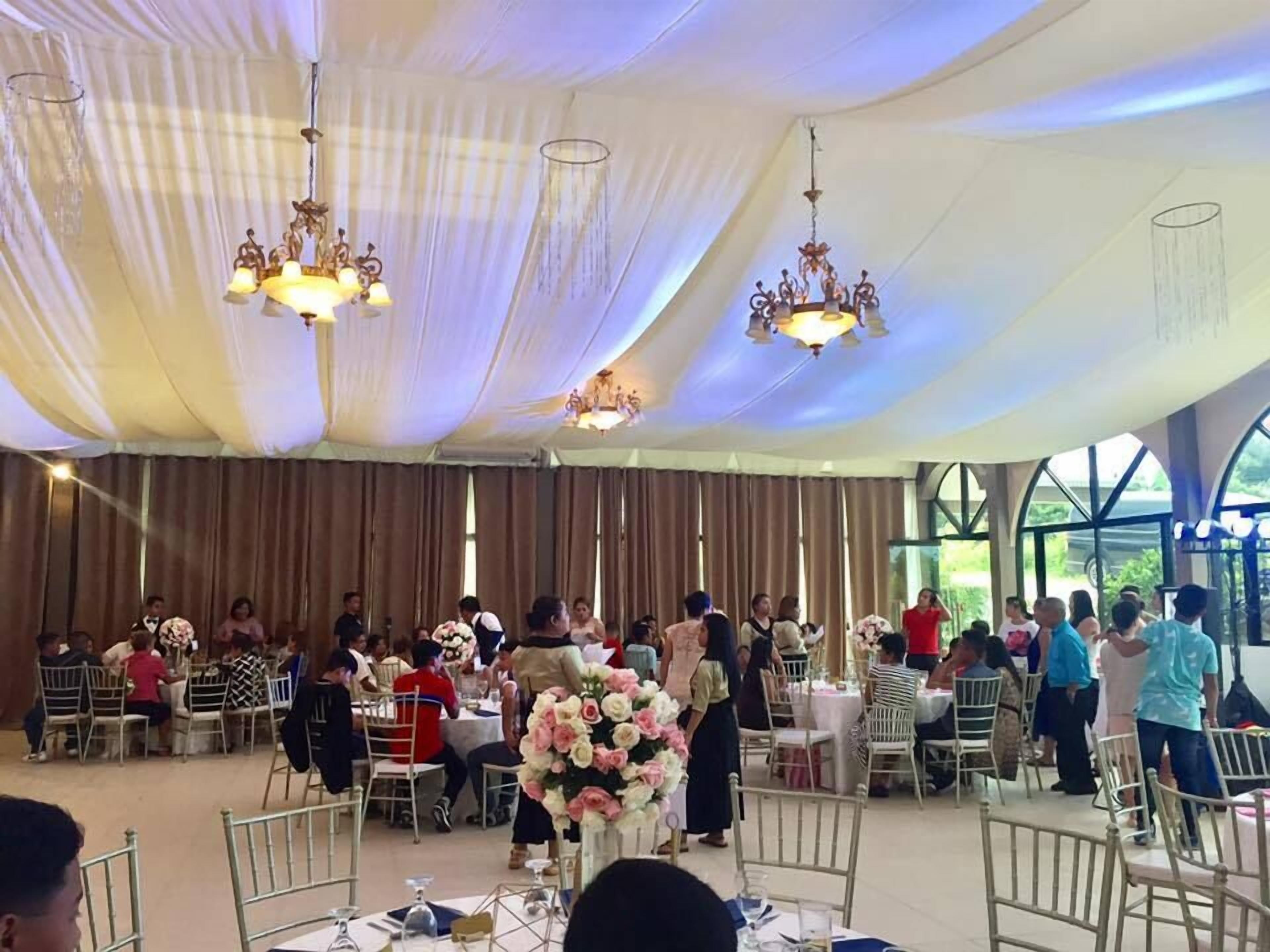 A banquet hall with tables and chairs, chandeliers, and a large floral arrangement.