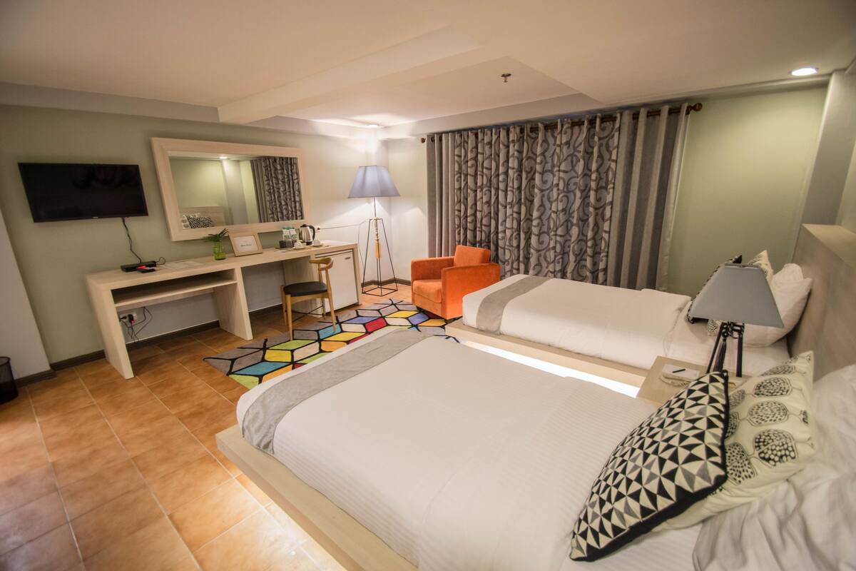 Ein Hotelzimmer mit einem Bett, einem Schreibtisch, einem Stuhl, einem Fernseher und einer Lampe.