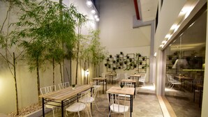 A modern indoor dining area with bamboo plants, hexagonal stone flooring, and white metal furniture. - Almont City Hotel (Butuan)