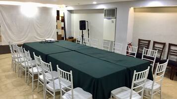 A conference room with a long table, white chairs, a speaker, and a fire extinguisher.