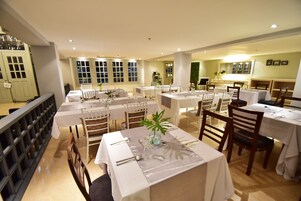 Un restaurante con varias mesas dispuestas para comer, con manteles blancos y sillas de madera.