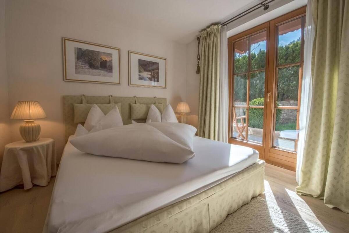A bedroom with a bed, two bedside lamps, a headboard, and two framed pictures on the wall.