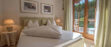 A bedroom with a bed, two bedside lamps, a headboard, and two framed pictures on the wall.