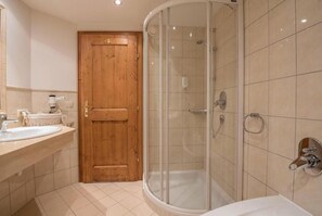 Ein Badezimmer mit Holztür, Duschkabine und Waschbecken.