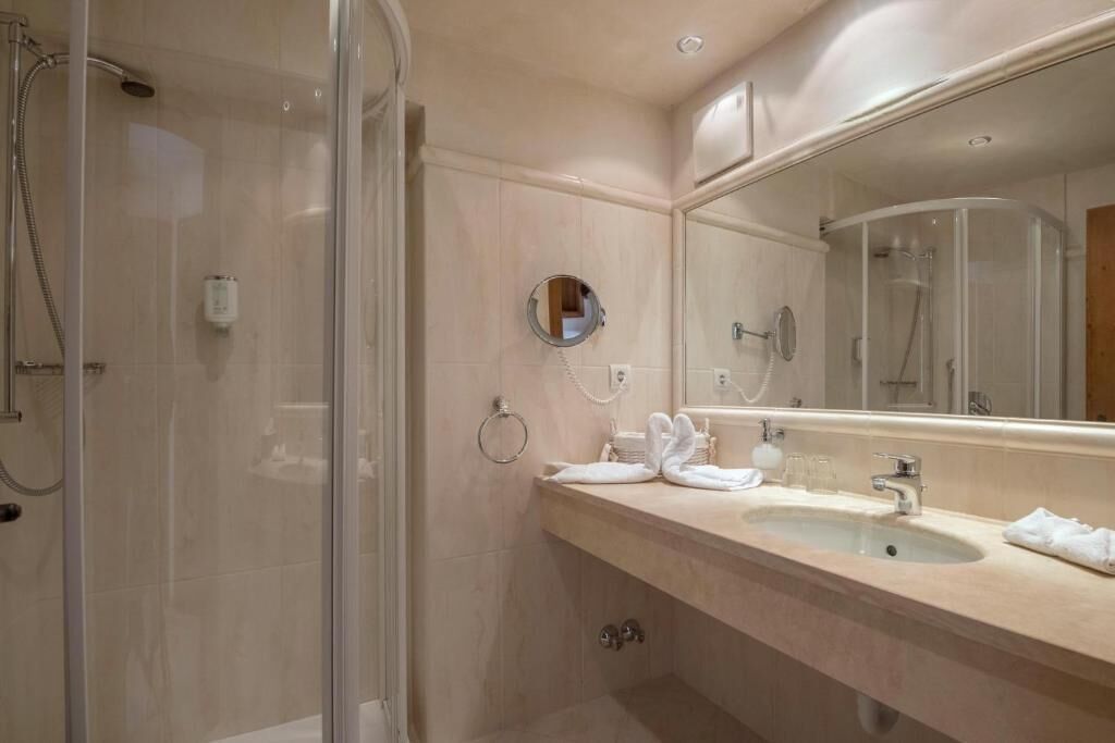 Een badkamer met een douchecabine van glas, een wastafel met spiegel en een handdoekrek.