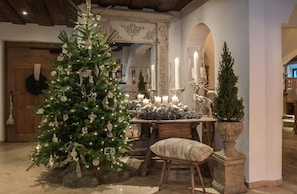 A Christmas tree with lights and ornaments, a table with candles, and a mirror with ornate details.