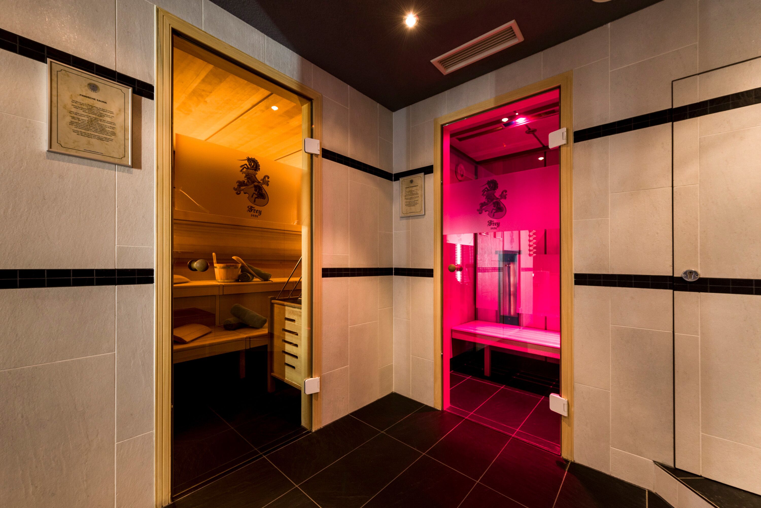 Un pasillo de hotel con un banco de madera, una habitación con iluminación roja y una placa en la pared.