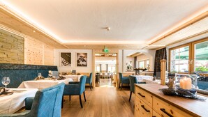 Un restaurante con suelos de madera, sillas tapizadas en azul y manteles blancos.