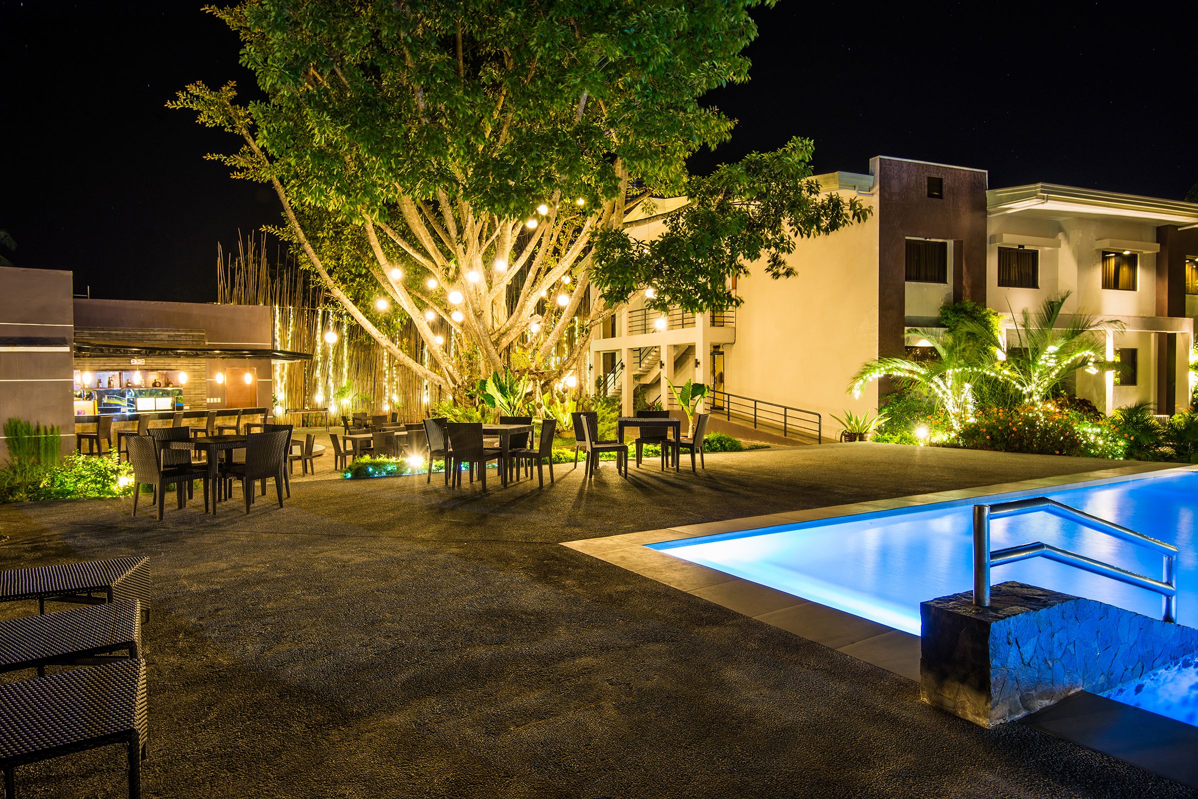 An outdoor pool area with seating and a staircase leading to a building.