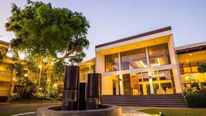 A modern building with a glass facade, a central water feature, and a well-maintained garden area. - Ariana Hotel (Dipolog)