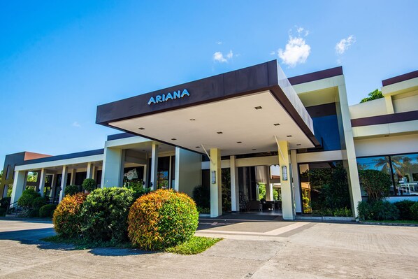 A modern hotel with a prominent "ARIANA" sign, covered entrance, and well-maintained landscaping. - Ariana Hotel (Dipolog)