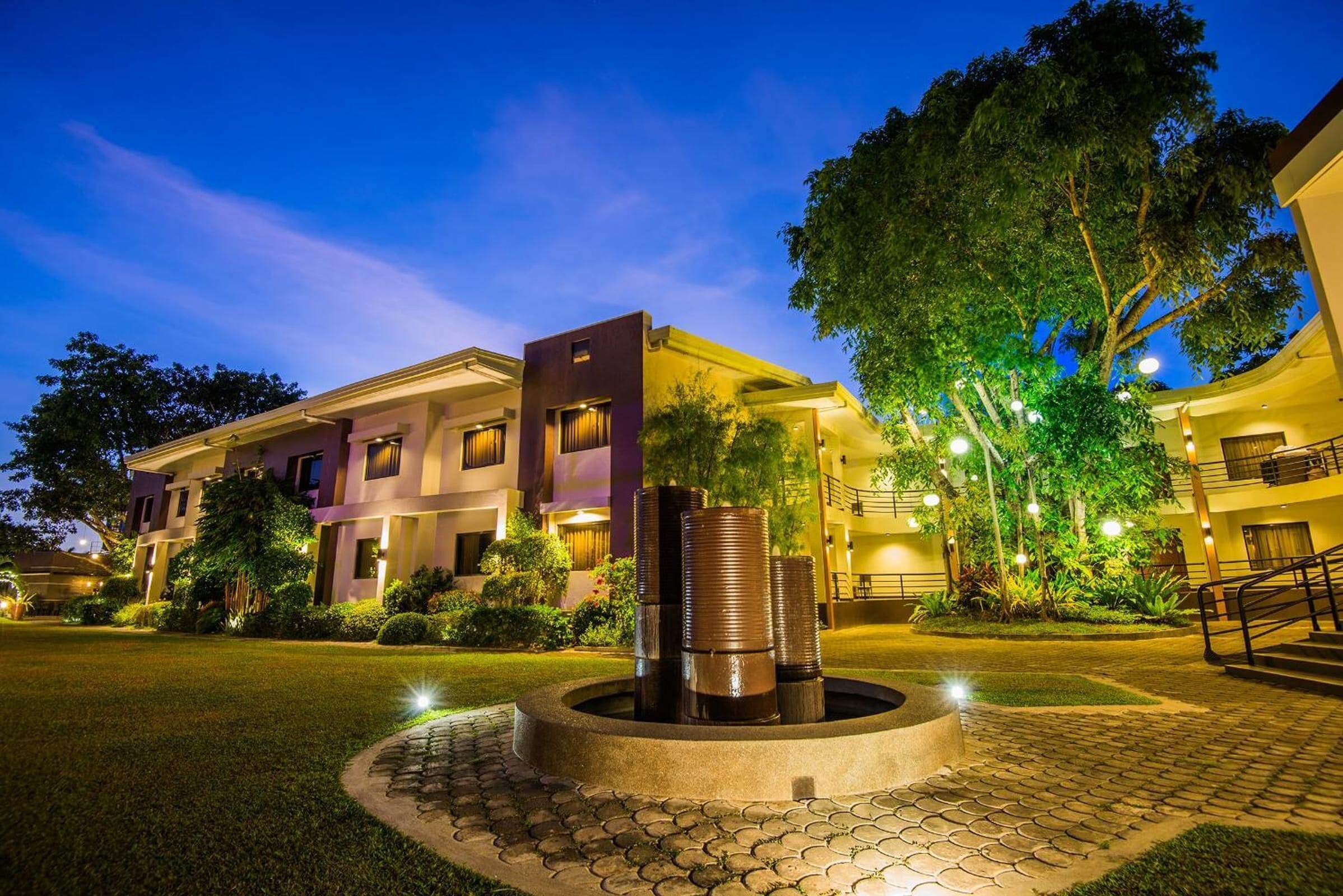 A modern hotel with a courtyard, a central water feature, and well-lit outdoor areas.