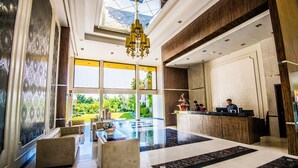 A spacious lobby with a reception desk, seating area, and a large window offering a view of the outdoors. - Ariana Hotel (Dipolog)