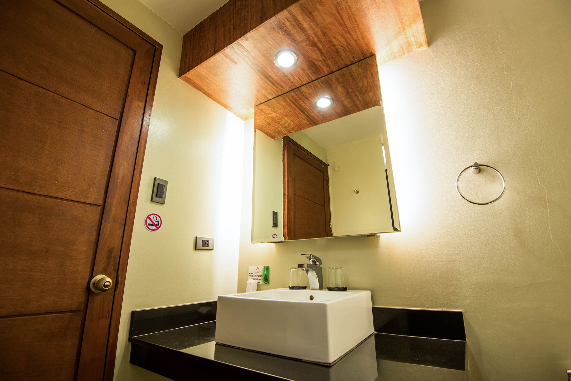 A bathroom with a wooden door, a white sink, and a mirror above it.