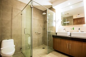 A modern bathroom with a glass-enclosed shower, a toilet, and wooden cabinets. - Ariana Hotel (Dipolog)