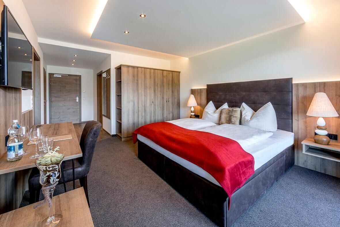 Une chambre d’hôtel avec un grand lit, un bureau avec une chaise, une télévision et une armoire.