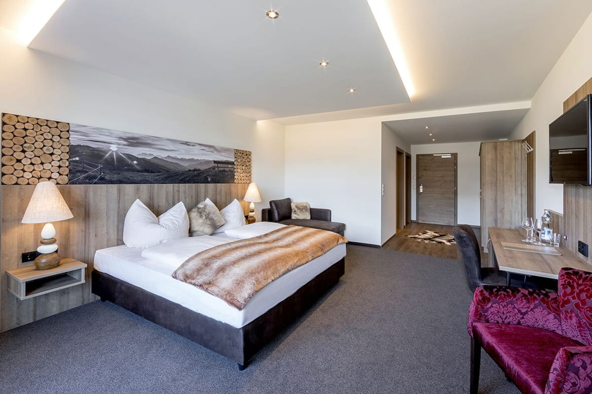 A modern hotel room with a large bed, a desk, and a TV.