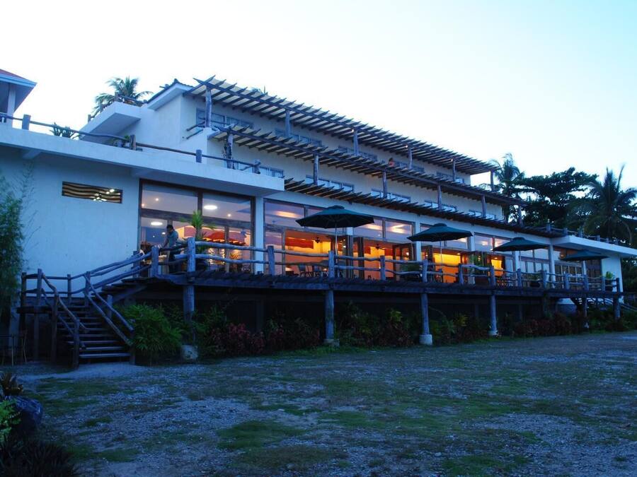A two-story building with a covered outdoor area, a staircase leading to the upper level, and outdoor seating with umbrellas.