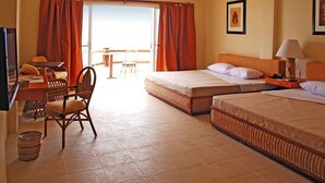 Ein Hotelzimmer mit zwei Betten, einem Schreibtisch, einem Stuhl und Blick ins Freie.