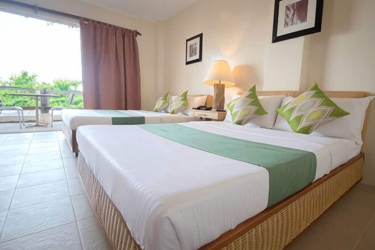 Quarto de hotel com duas camas, varanda, mesa e abajur.