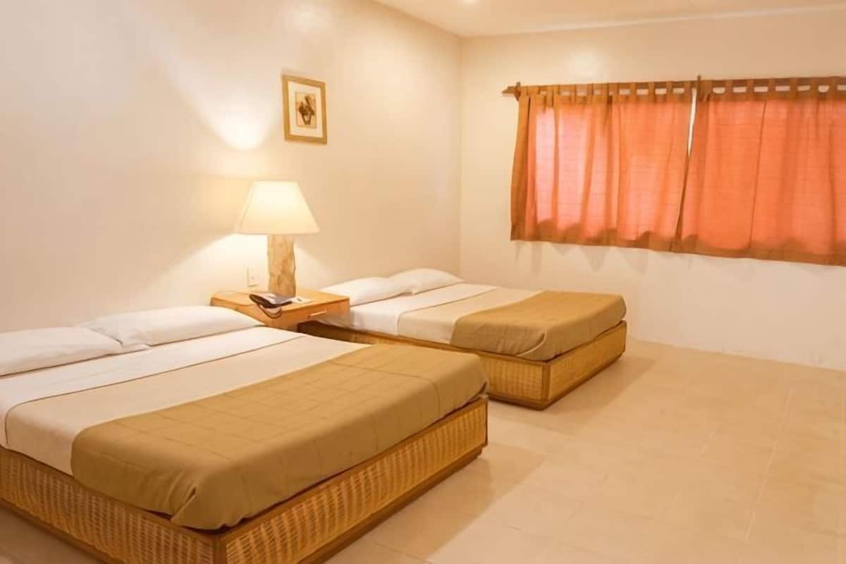 Quarto com duas camas de solteiro, uma mesa de cabeceira com abajur, uma janela com cortinas e um quadro na parede.