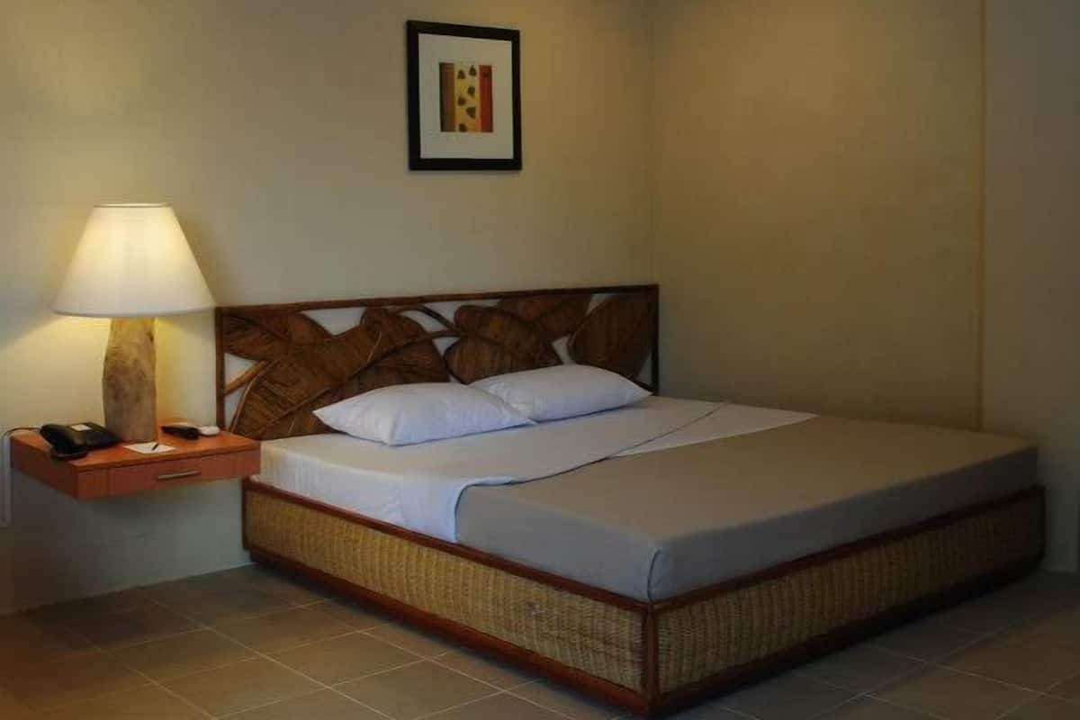 Uma cama de solteiro com cabeceira de madeira, uma mesa de cabeceira com abajur e um quadro na parede.