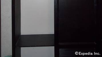 Ein dunkler, hölzerner Kleiderschrank mit einer weißen Kleiderstange und einer Ablagefläche.