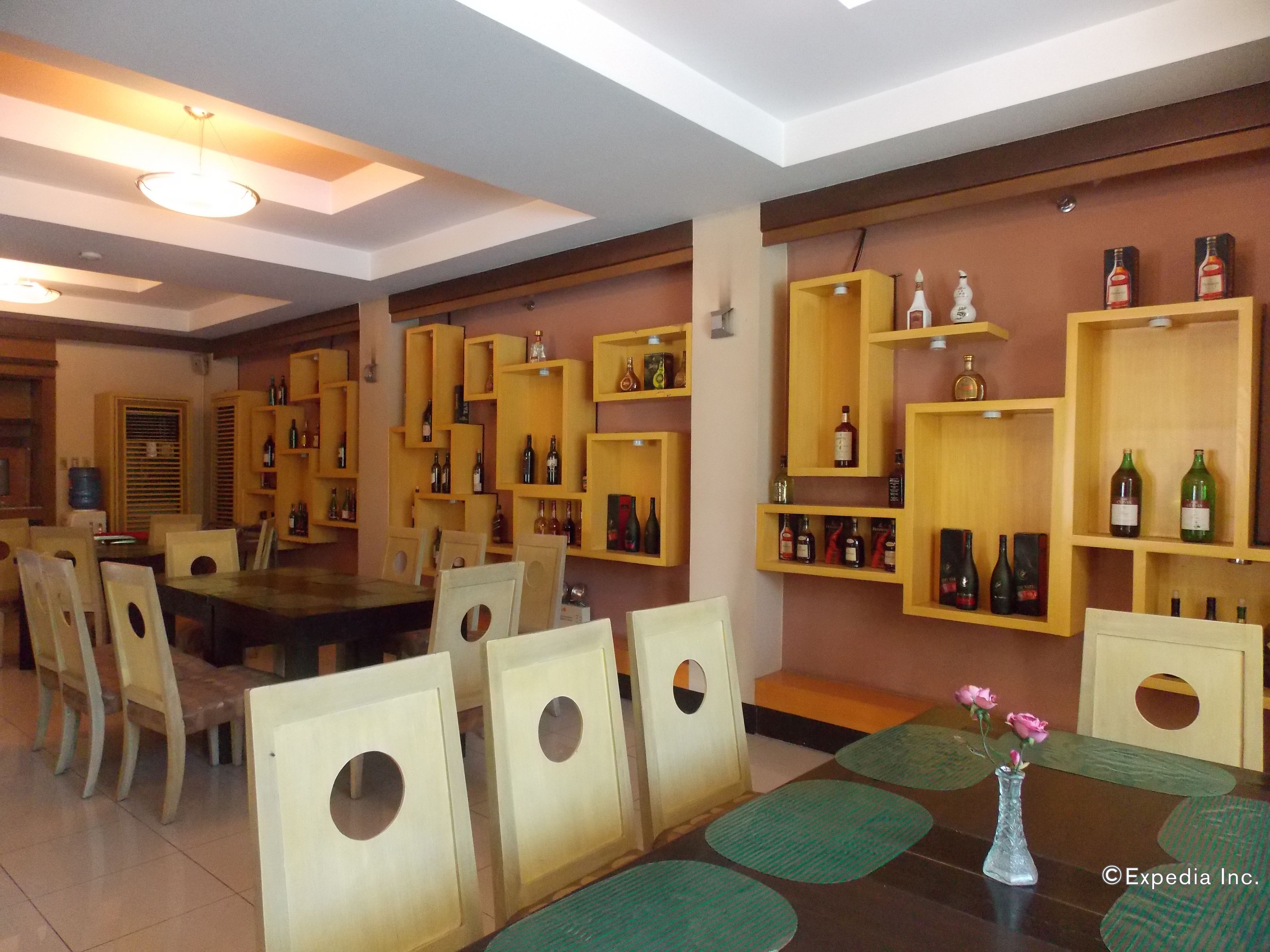 A dining area with wooden chairs and a table, surrounded by shelves with bottles.