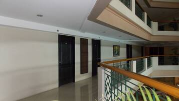 A multi-level interior with a wooden staircase, tiled floors, and a painting on the wall.