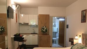Una habitación pequeña con cama, kitchenette y baño.