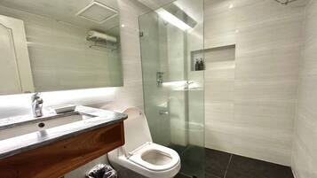 A modern bathroom with a glass-enclosed shower, a wooden vanity, and a toilet.