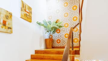 A wooden staircase with a handrail, a potted plant, and patterned wallpaper.