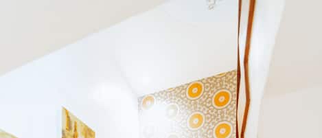 A wooden staircase with a handrail, a potted plant, and patterned wallpaper.