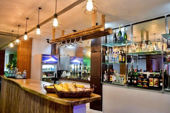 A bar area with wooden bar counter, hanging lights, and shelves stocked with bottles. - Bamboo Beach Resort and Restaurant (Balabag)