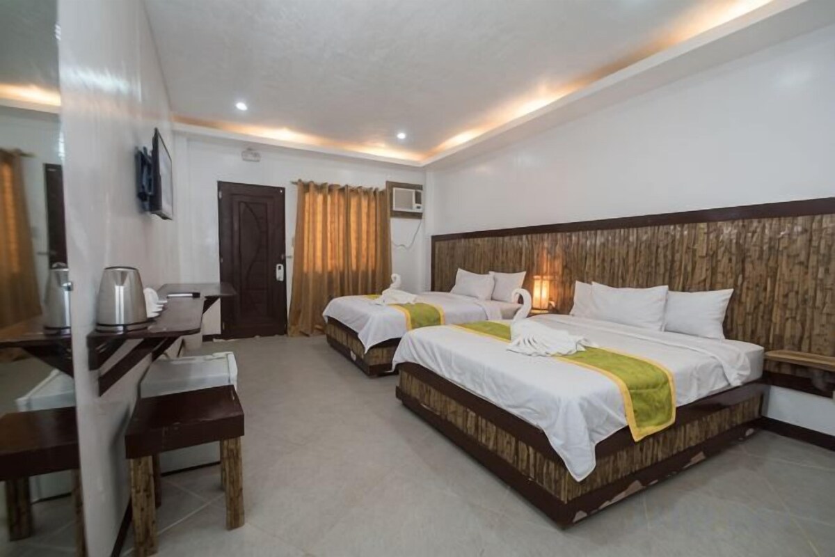 Habitación de hotel con dos camas, un escritorio, una silla y un televisor.