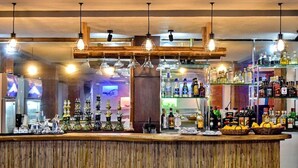A bar area with a wooden counter, hanging light fixtures, and shelves stocked with bottles. - Bamboo Beach Resort and Restaurant (Balabag)