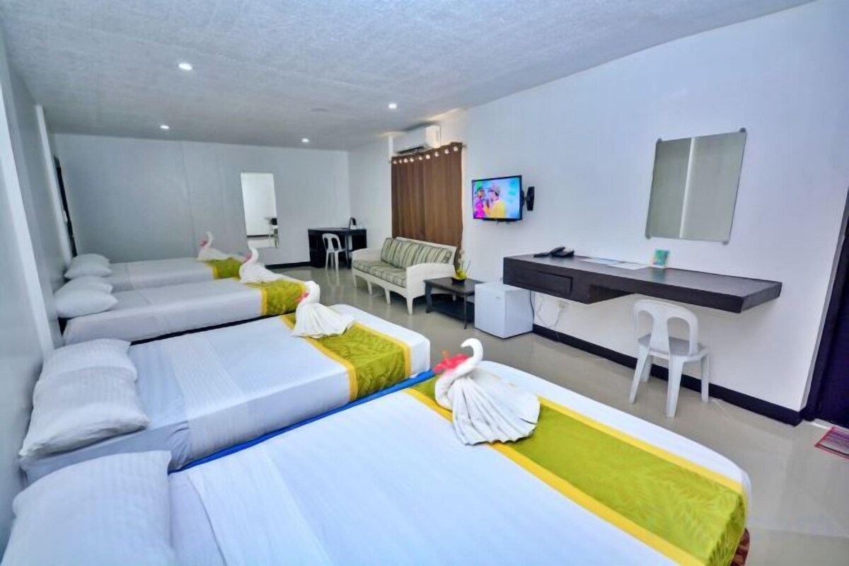 Una habitación de hotel con dos camas, un escritorio, una silla, un televisor y una mesita.
