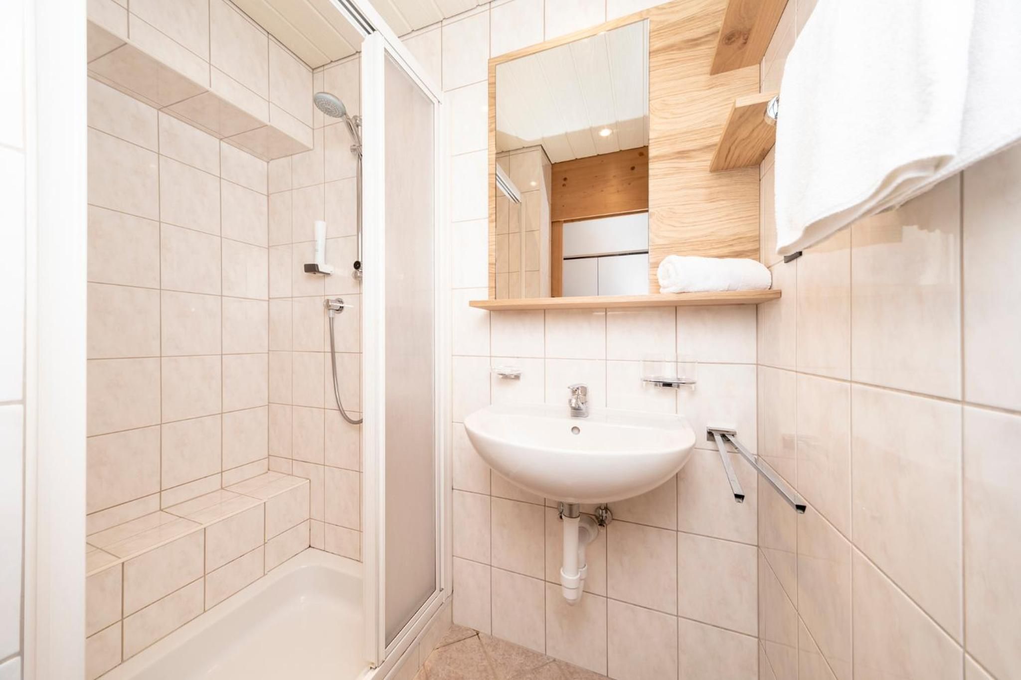 Un baño moderno con ducha, lavamanos y espejo.