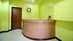 A reception area with a wooden reception desk, a clock on the wall, and a door. - Luis Bay Travellers Lodge Coron (Coron)