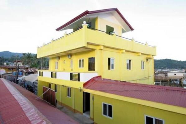 A yellow multi-story building with a red roof, balconies, and windows. - Luis Bay Travellers Lodge Coron (Coron)