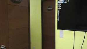 A hallway with a wooden door labeled "Twin Peak," a television mounted on the wall, and a sign above the door reading "MyVish." - Luis Bay Travellers Lodge Coron (Coron)