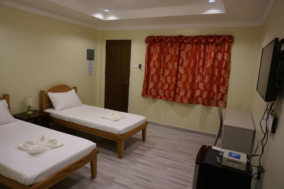 A hotel room with two single beds, a television, and a desk with a computer.