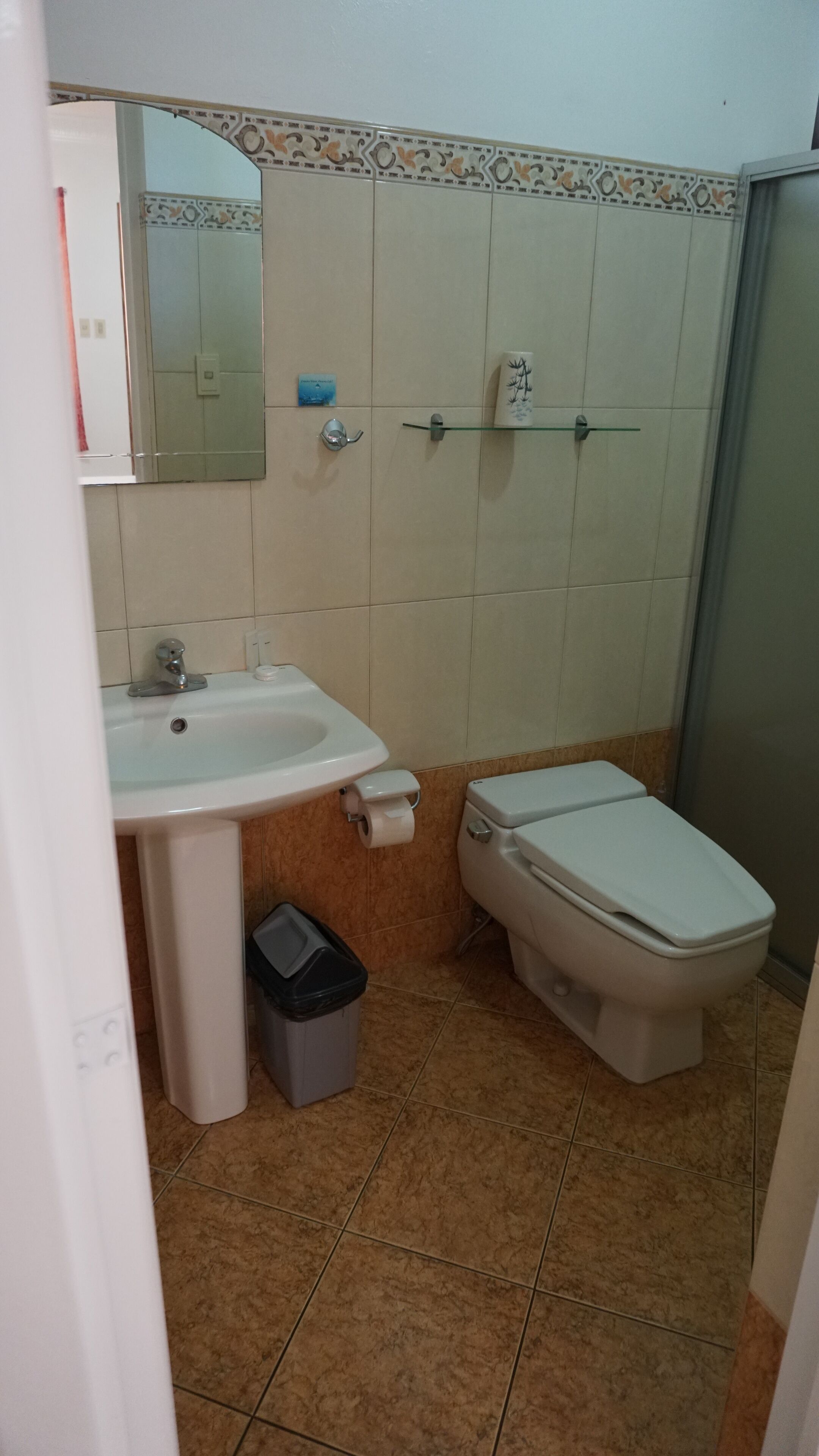 A small bathroom with a sink, toilet, and a trash bin.